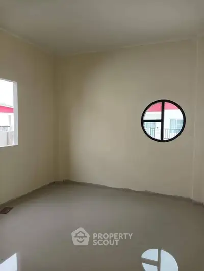 Spacious empty room with unique round window and glossy floor