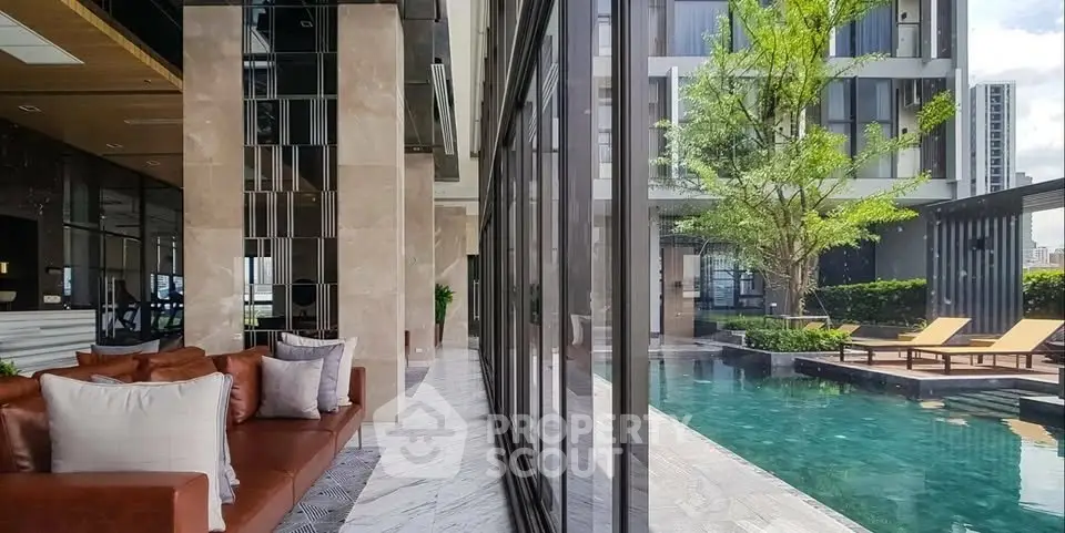 Luxurious modern building with poolside seating and lush greenery, perfect for relaxation and leisure.