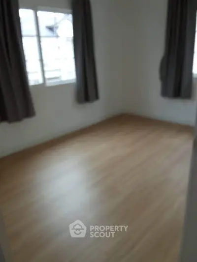 Spacious empty room with wooden flooring and large windows, ideal for customization.