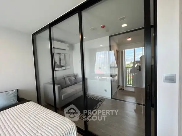 Modern apartment with glass partition and cozy living area, featuring a balcony view.