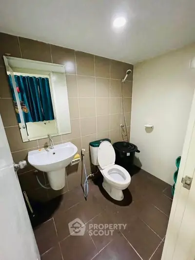 Modern bathroom with sleek fixtures and tiled walls, featuring a shower and toilet in a compact layout.