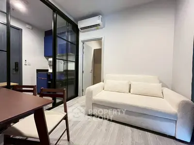 Modern living room with cozy white sofa and sleek glass partition in stylish apartment.