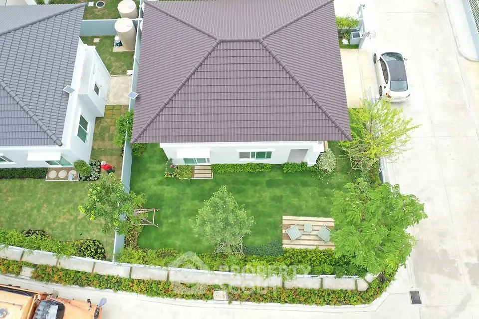Aerial view of a modern house with landscaped garden and driveway.