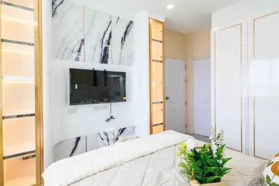 Luxurious bedroom with modern TV setup and elegant marble accents
