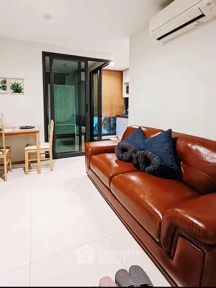 Modern living room with leather sofa and dining area, featuring sleek design and cozy ambiance.