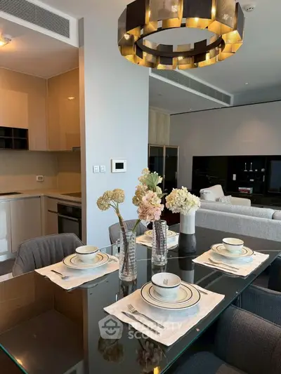 Luxurious dining area with elegant table setting and modern chandelier in a stylish open-plan apartment.