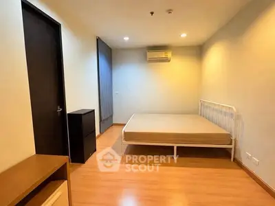 Spacious bedroom with wooden flooring and air conditioning in modern apartment.