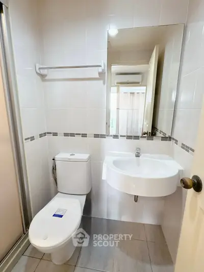 Modern bathroom with sleek fixtures and tiled walls, featuring a compact design for efficient space use.