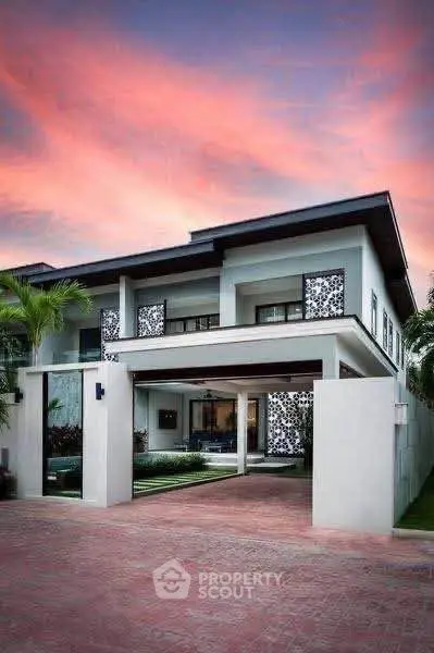 Modern two-story house with stylish facade and sunset sky backdrop.