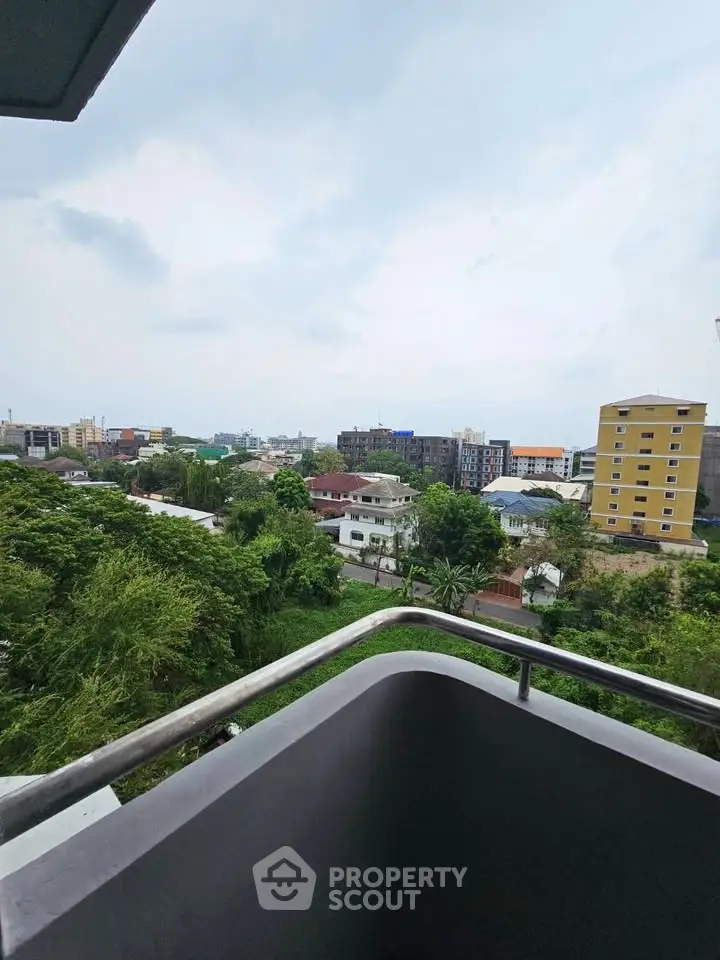 Stunning urban view from a high-rise balcony overlooking lush greenery and cityscape.