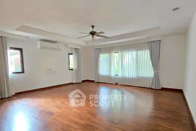 Spacious empty living room with wooden flooring and large windows