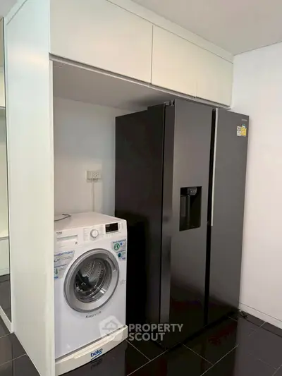 Modern kitchen with sleek black fridge and washing machine in compact layout.