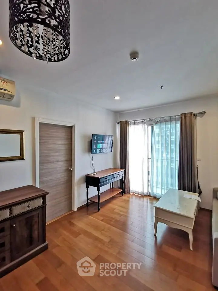Charming living room with wooden flooring and natural light from large windows.