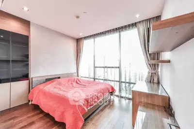 Spacious bedroom with large windows and modern furnishings, offering abundant natural light and city views.
