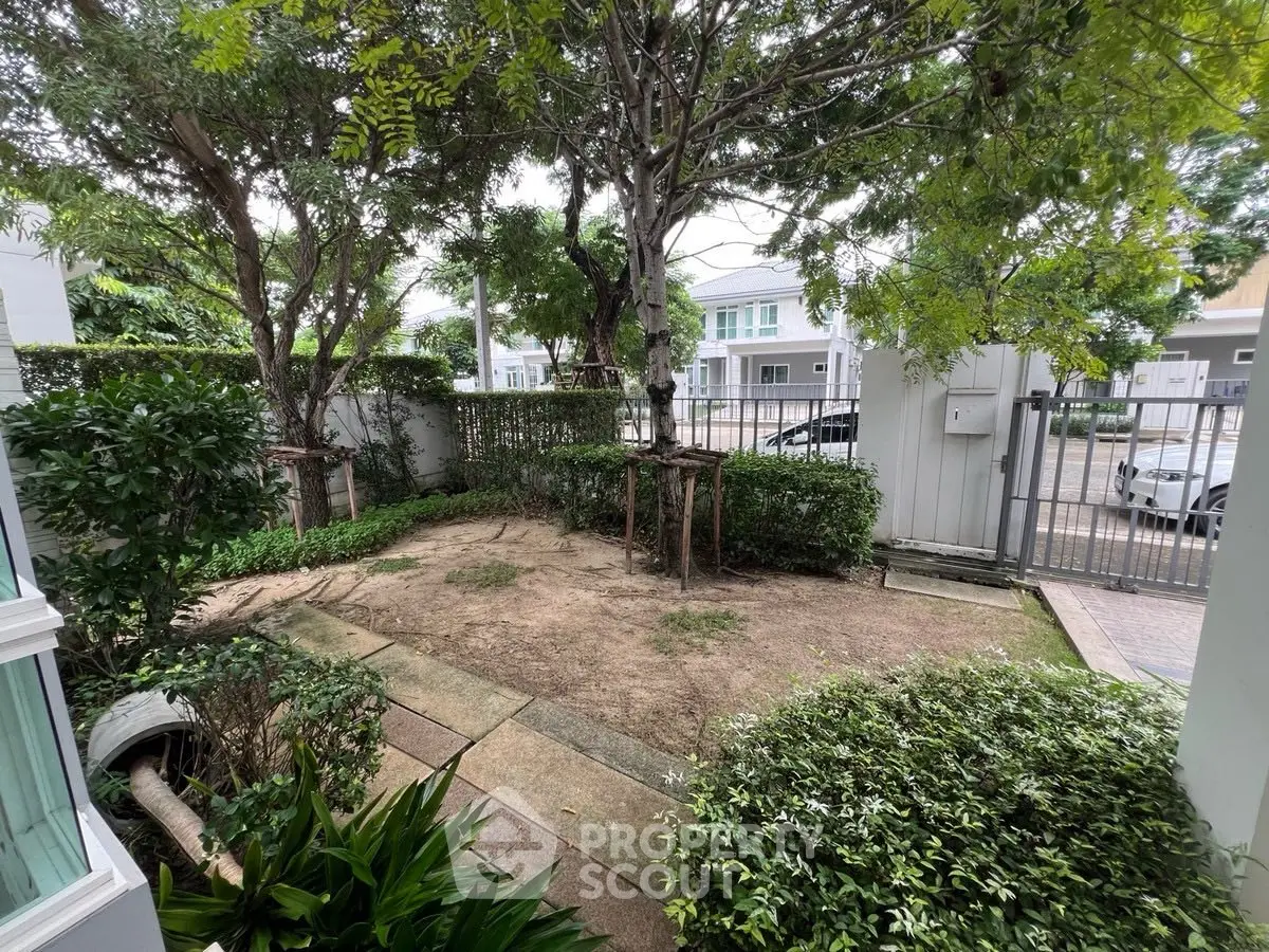 Charming garden space with lush greenery and paved walkway in a residential area.