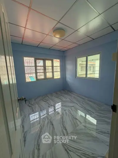 Spacious bedroom with elegant marble flooring and ample natural light.