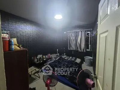 Cozy bedroom with dark walls and minimalistic decor, featuring a double bed and soft lighting.