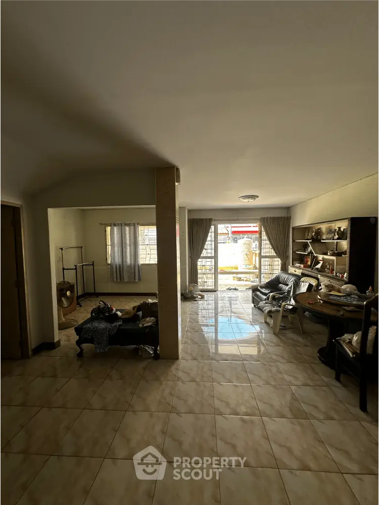 Spacious living room with tiled flooring and large windows for natural light.