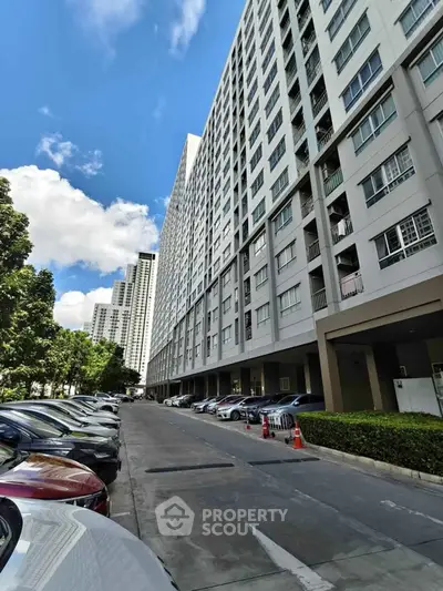 Modern high-rise apartment building with parking area and clear blue sky