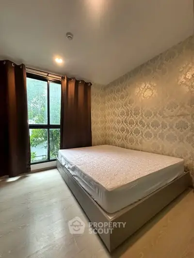 Cozy bedroom with elegant wallpaper and large window for natural light.