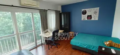 Spacious bedroom with balcony and modern decor, featuring a study desk and large window view.