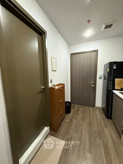 Modern apartment entrance with sleek wooden flooring and stylish kitchen area.