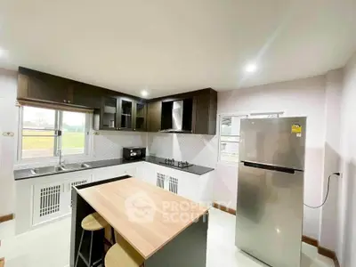 Modern kitchen with sleek cabinetry, gas stove, and stainless steel fridge in a bright, open layout.