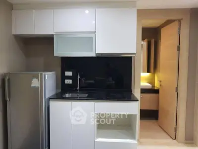 Modern compact kitchen with sleek cabinetry and built-in appliances in a stylish apartment.