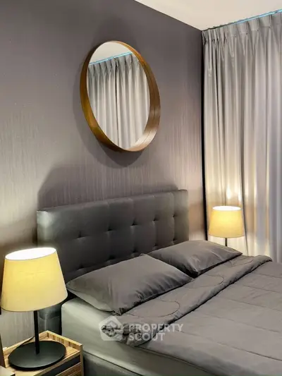 Modern bedroom with stylish decor, featuring a plush bed, elegant lamps, and a round mirror on a textured wall.