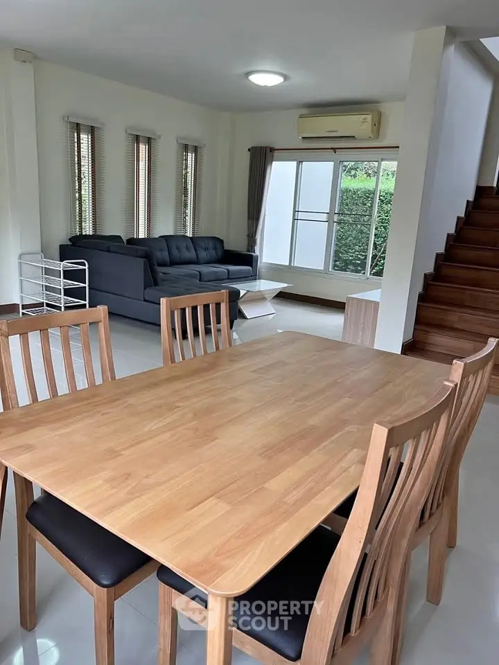 Spacious living room with modern wooden dining set and cozy sofa, perfect for family gatherings.