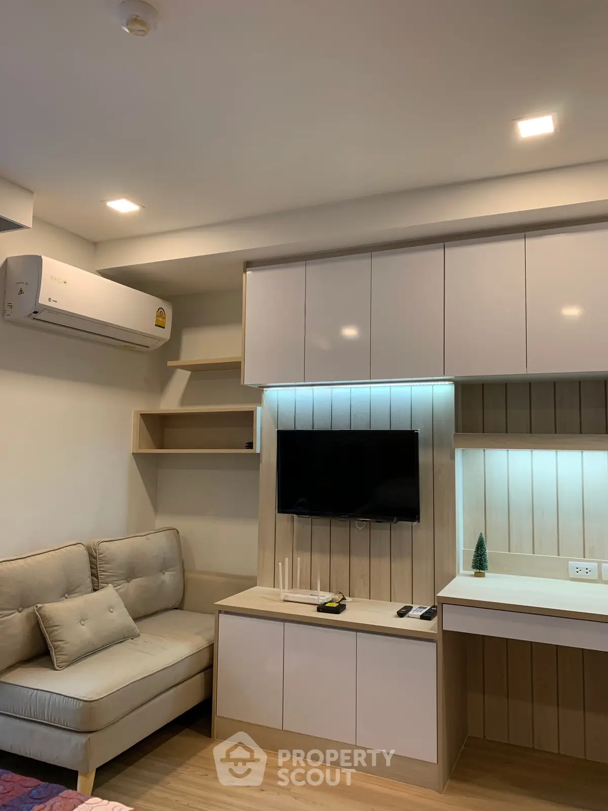 Modern living room with sleek cabinetry and wall-mounted TV, featuring cozy seating and ambient lighting.