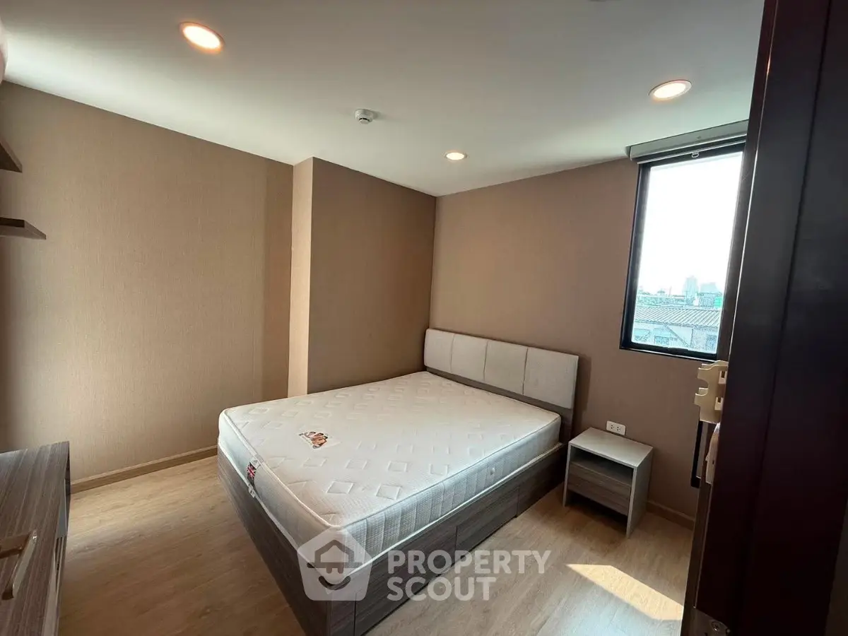 Modern bedroom with large window and natural light, featuring a comfortable bed and stylish decor.