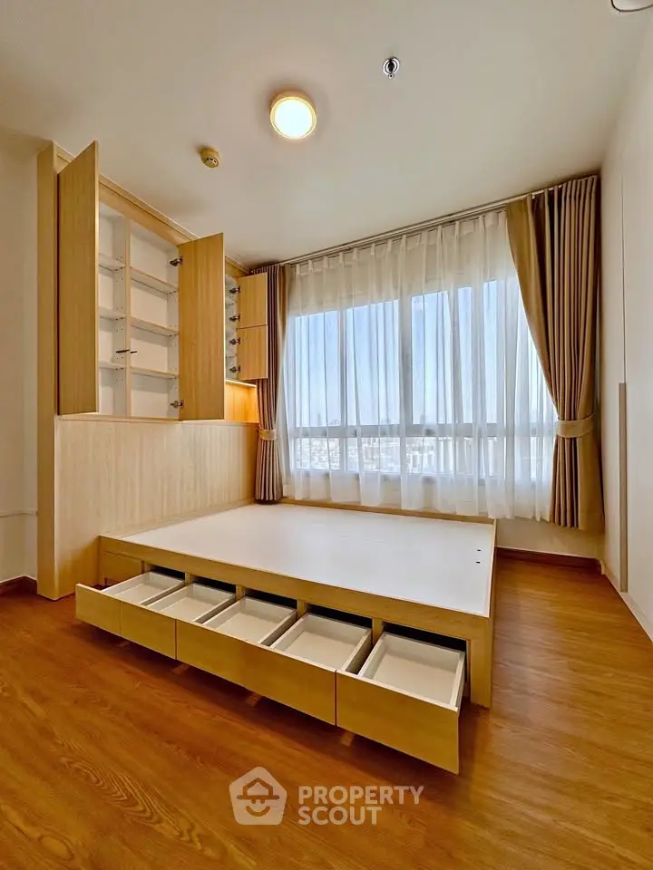 Modern bedroom with built-in storage and large window offering natural light.