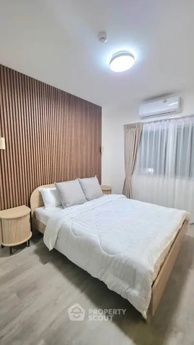 Modern bedroom with stylish wood paneling and cozy bedding in a bright, airy space.