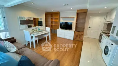 Modern living room with open kitchen, wooden flooring, and cozy dining area.