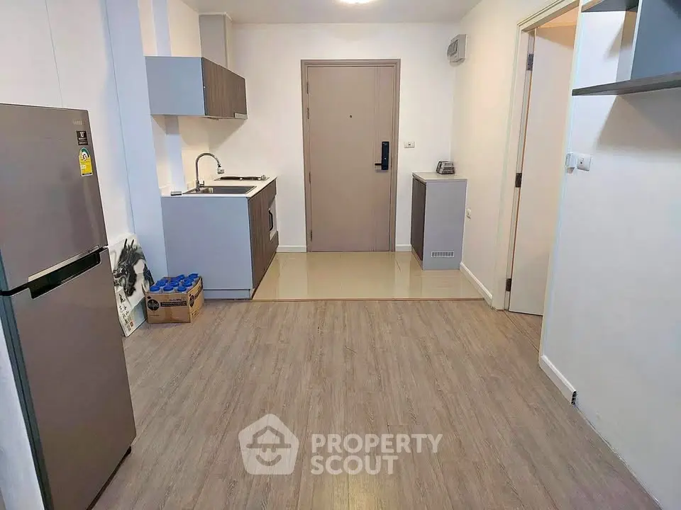Modern apartment entrance with compact kitchen and wooden flooring