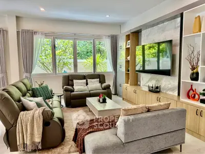 Spacious living room with modern furniture and large windows offering garden views.