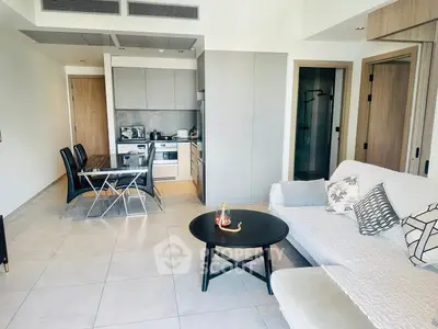 Modern open-layout living room with sleek kitchen and dining area, featuring contemporary furniture and stylish decor.