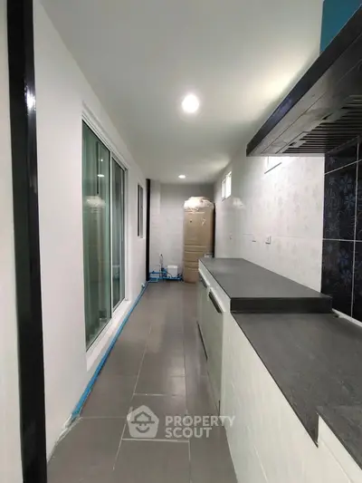 Modern kitchen with sleek countertops and sliding glass doors in a narrow layout.