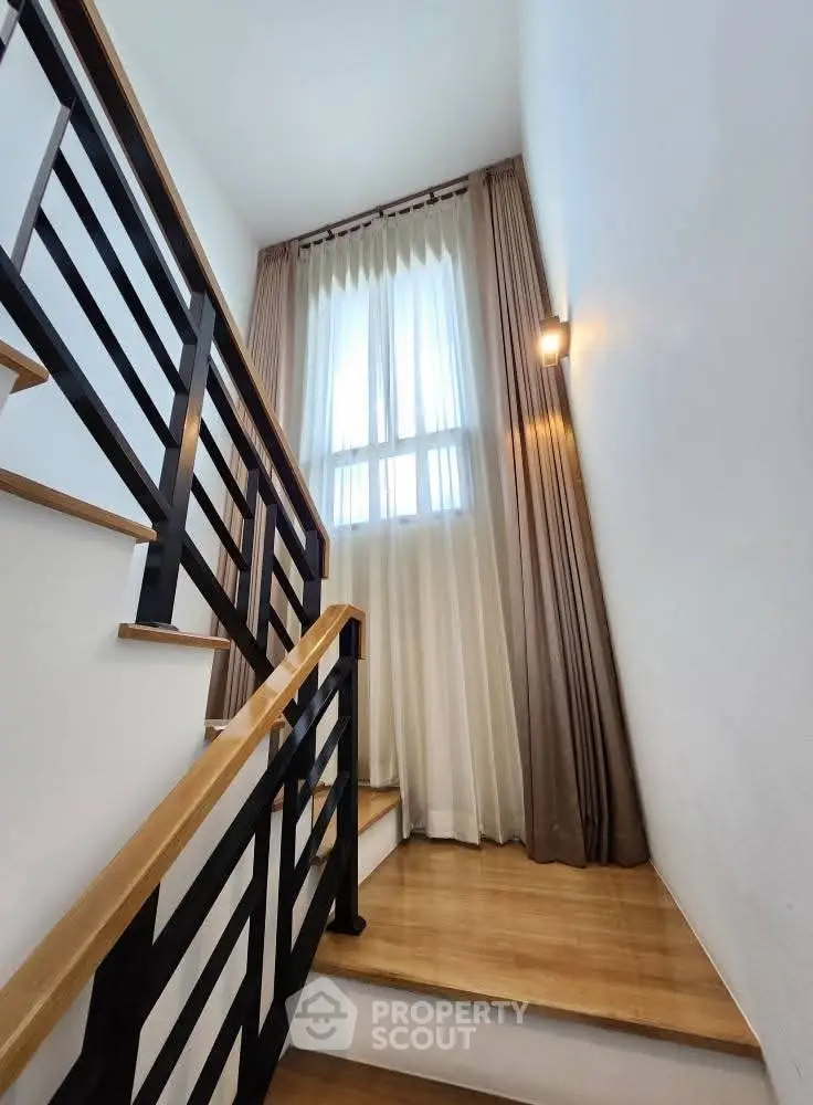 Elegant staircase with wooden steps and modern railing in a bright home interior.