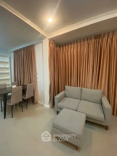 Modern living room with cozy gray sofa and elegant dining area, featuring stylish curtains and ambient lighting.
