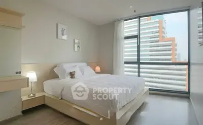 Modern bedroom with large windows and city view, featuring cozy decor and ample natural light.