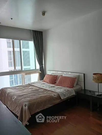 Spacious bedroom with large window and modern decor in high-rise apartment