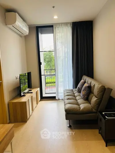 Modern living room with sleek furniture and large window offering natural light and a view.