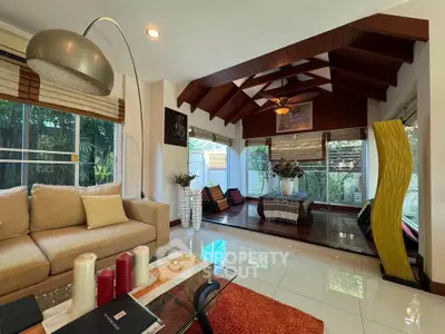 Elegant living room with vaulted wooden ceiling and large windows overlooking lush garden.