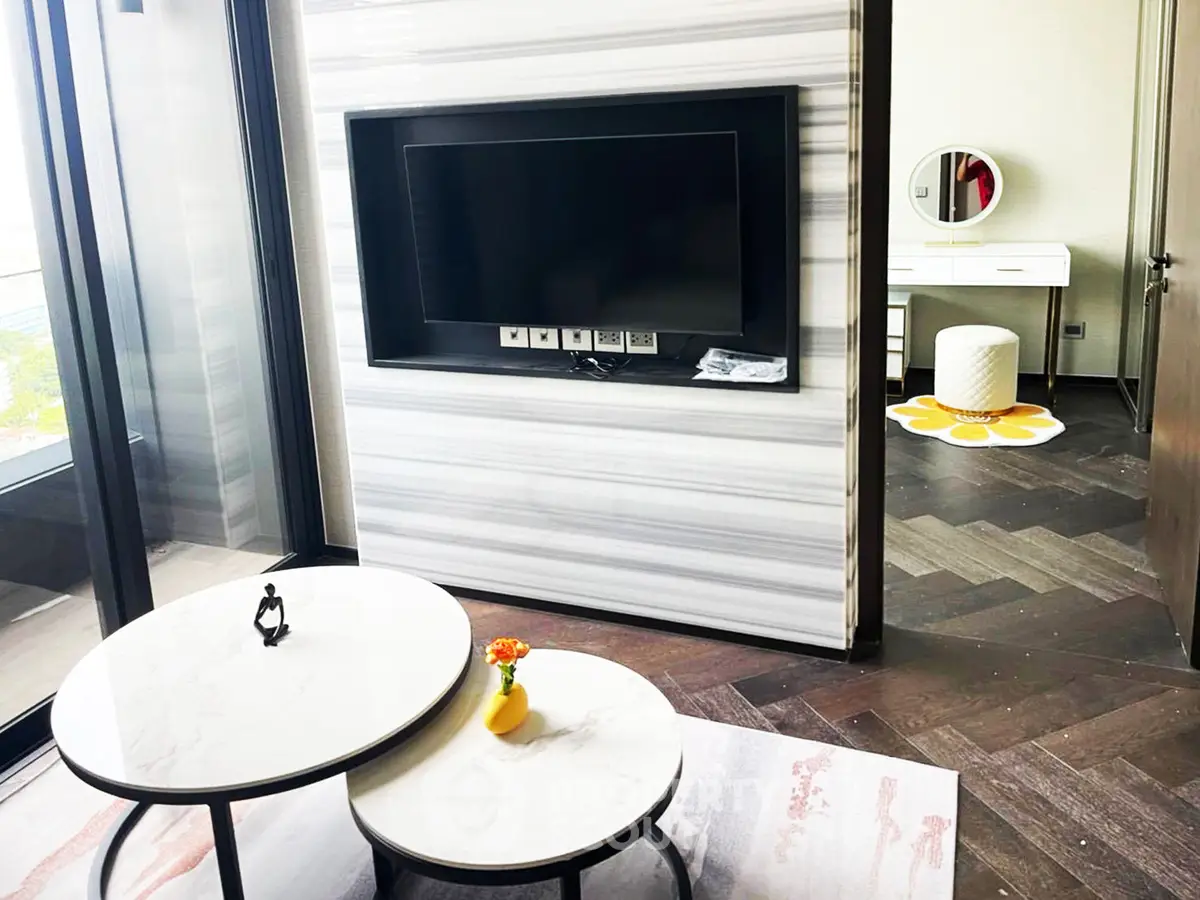 Modern living room with stylish marble tables and built-in TV, adjacent to a chic vanity area.