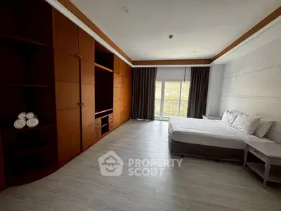 Spacious bedroom with large wooden wardrobe and balcony access