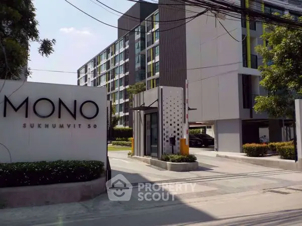 Modern condominium entrance with sleek design and lush greenery at Mono Sukhumvit 50.