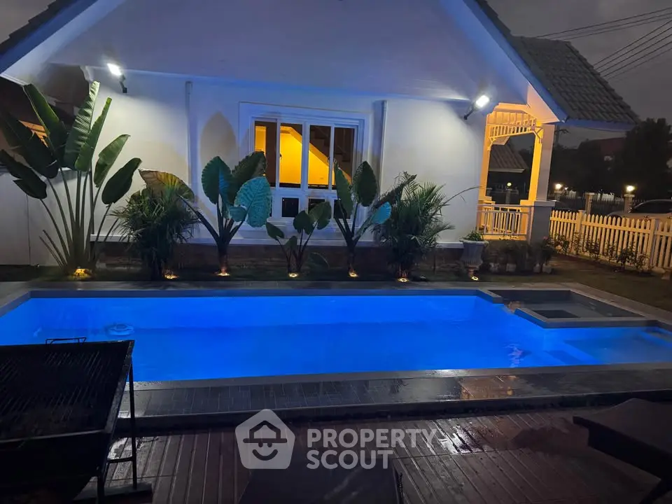 Charming evening view of a private backyard pool with ambient lighting and lush greenery.