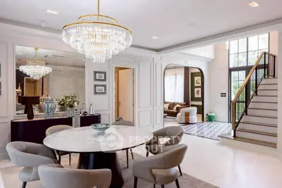 Luxurious dining room with elegant chandelier and modern decor in a spacious open-plan home.